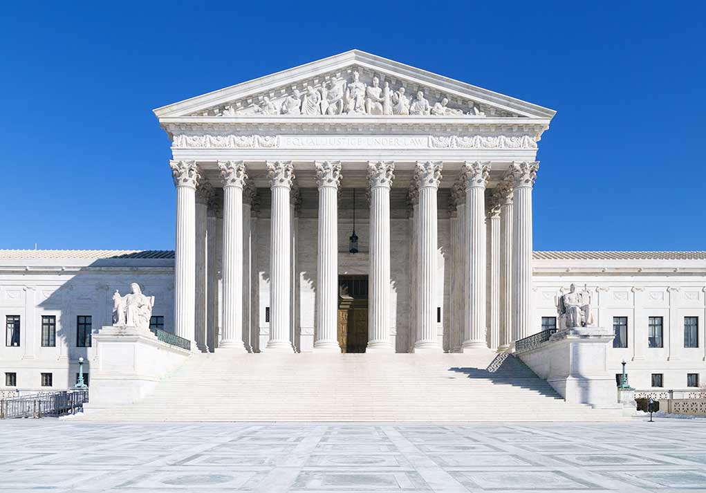 The Supreme Court building featuring marble columns and a clear blue sky