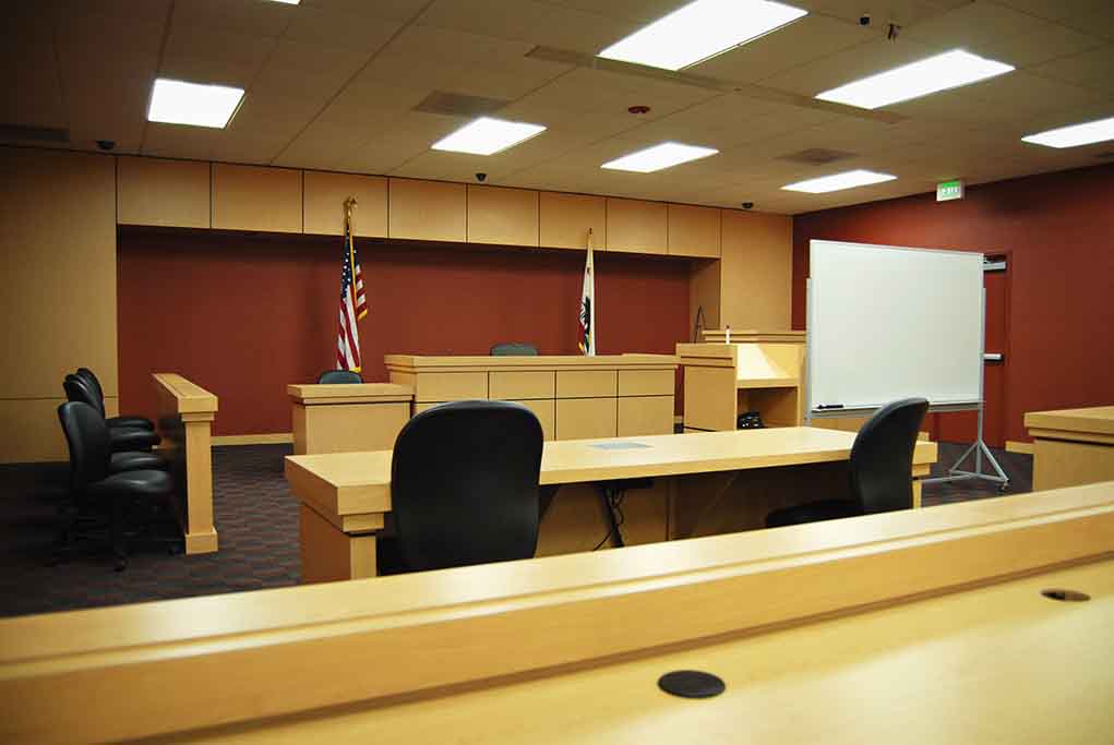Interior view of an empty courtroom with wooden furniture and American flags