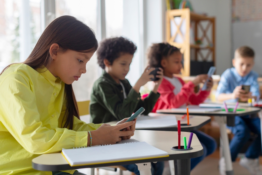 Students using smartphones at classroom desks