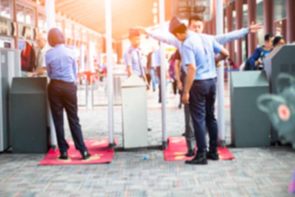 Security officers screen people at walk-through metal detectors