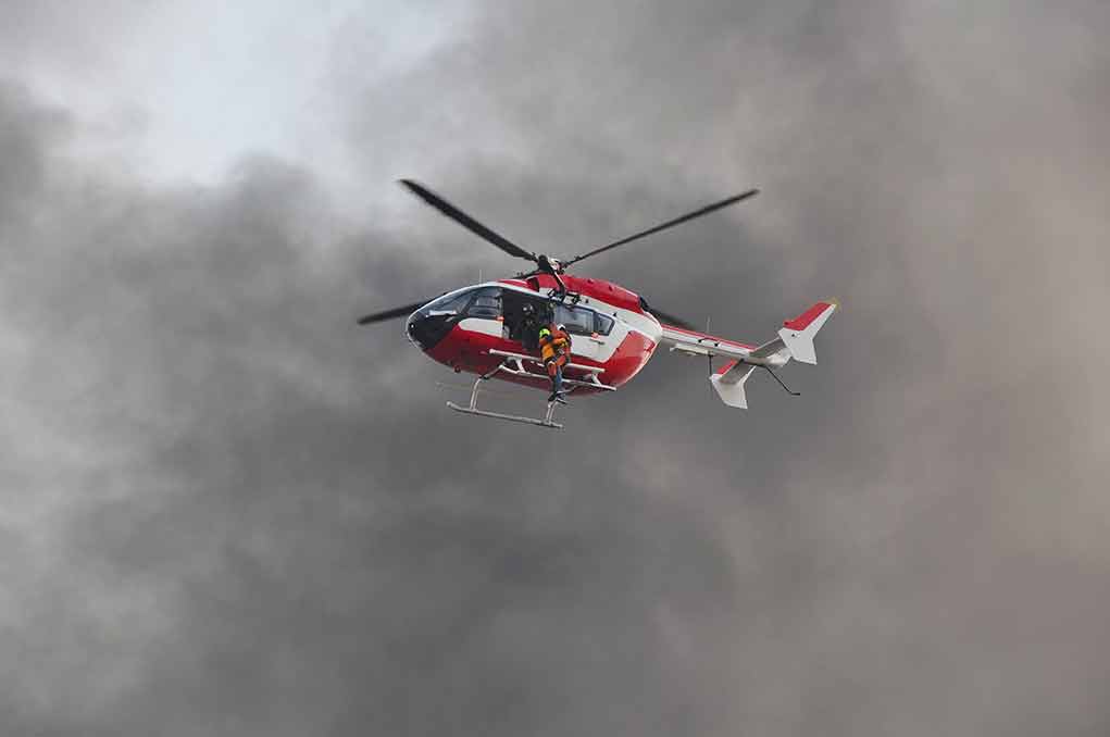 Rescue helicopter hovers amid thick smoke
