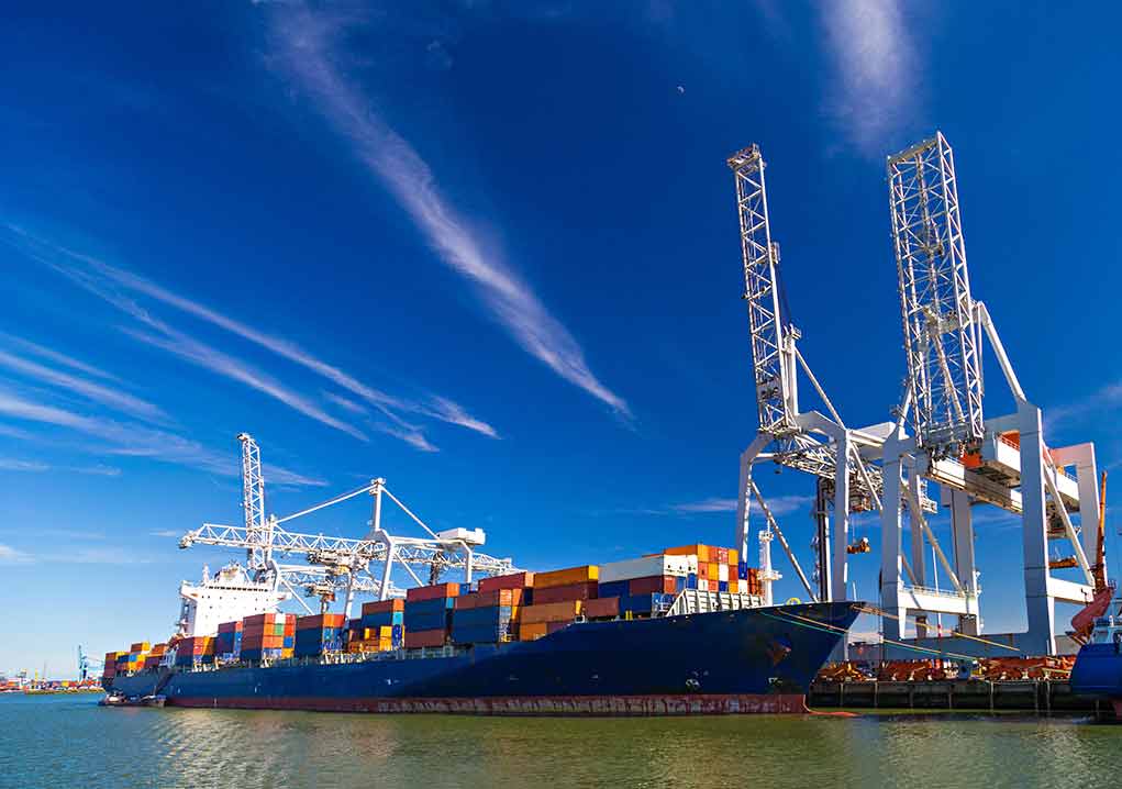 Container ship docked at port with cranes loading cargo