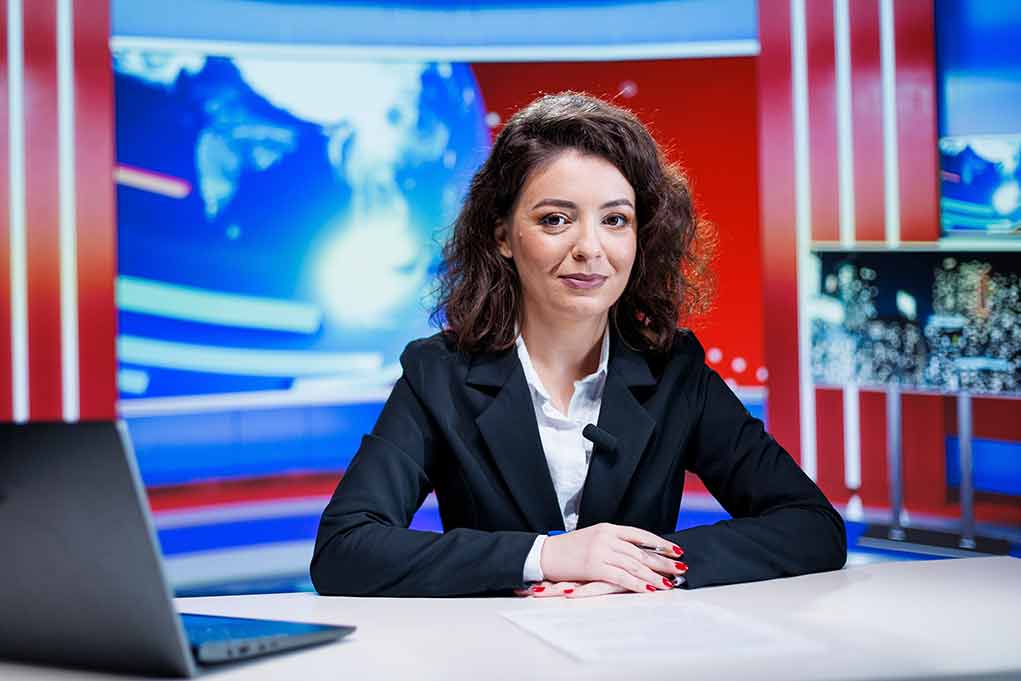 News anchor seated at a broadcast desk
