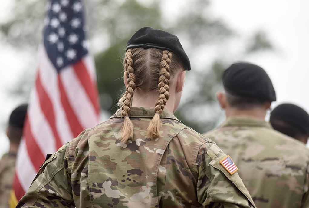 soldier in camouflage with braided hair and beret